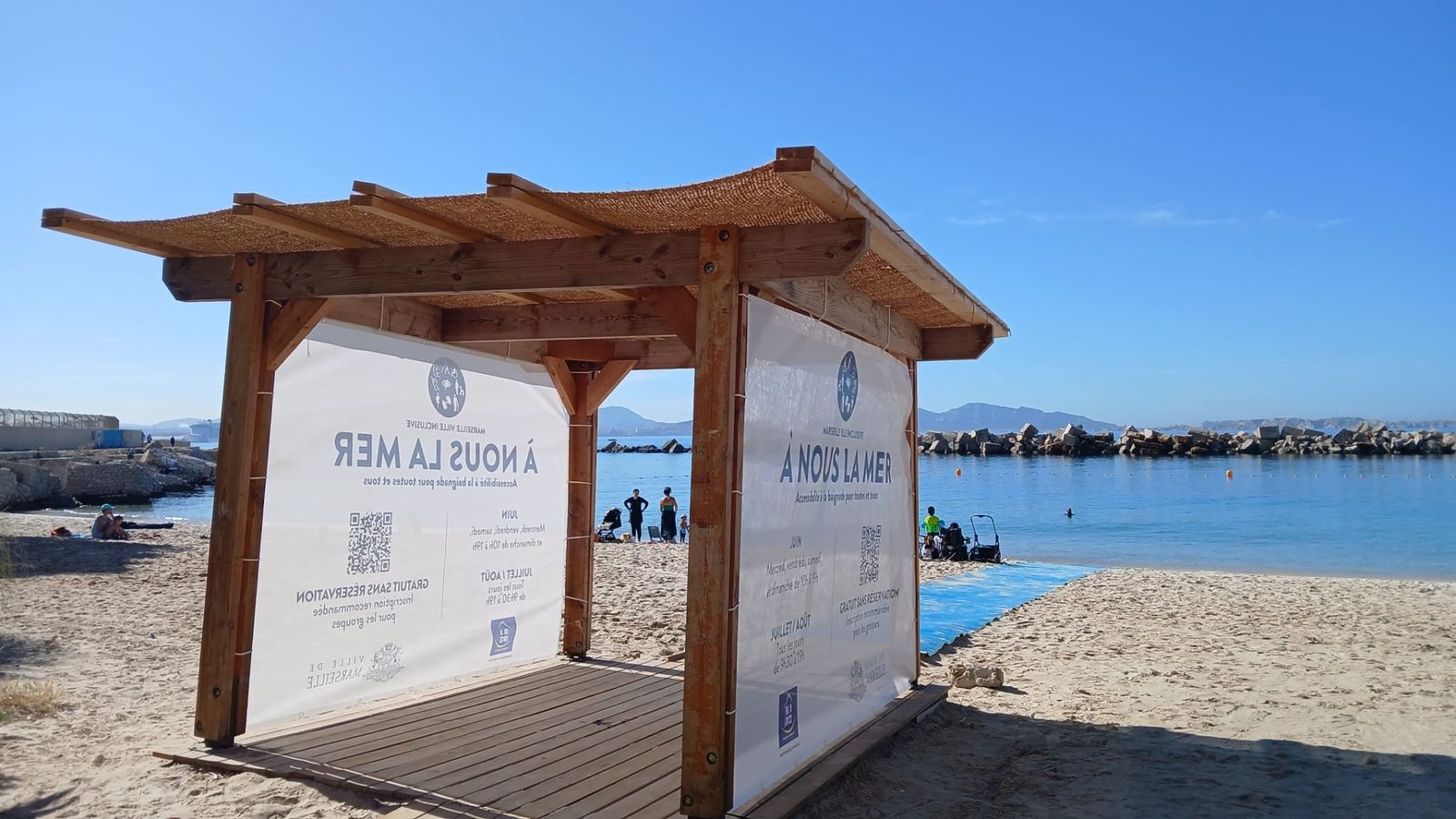Bâches imprimées tendues sur une structure en bois installée sur la plage